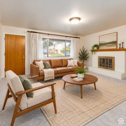 Living area featuring white painted brick fireplace, wood mantel, large picture window, and neutral carpeting