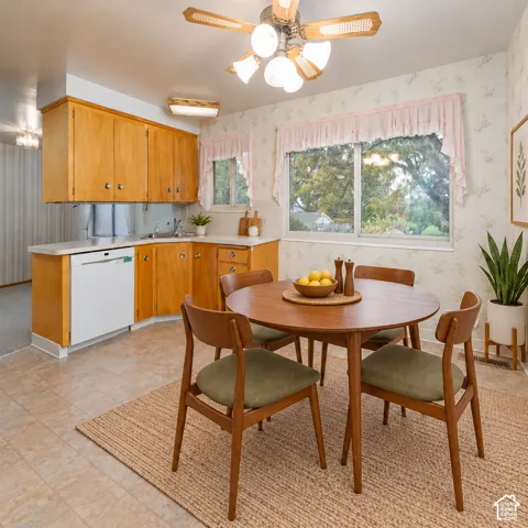 Kitchen featuring natural wood cabinetry, integrated dishwasher, solid surface countertops, and dual-pane windows with exterior natural light