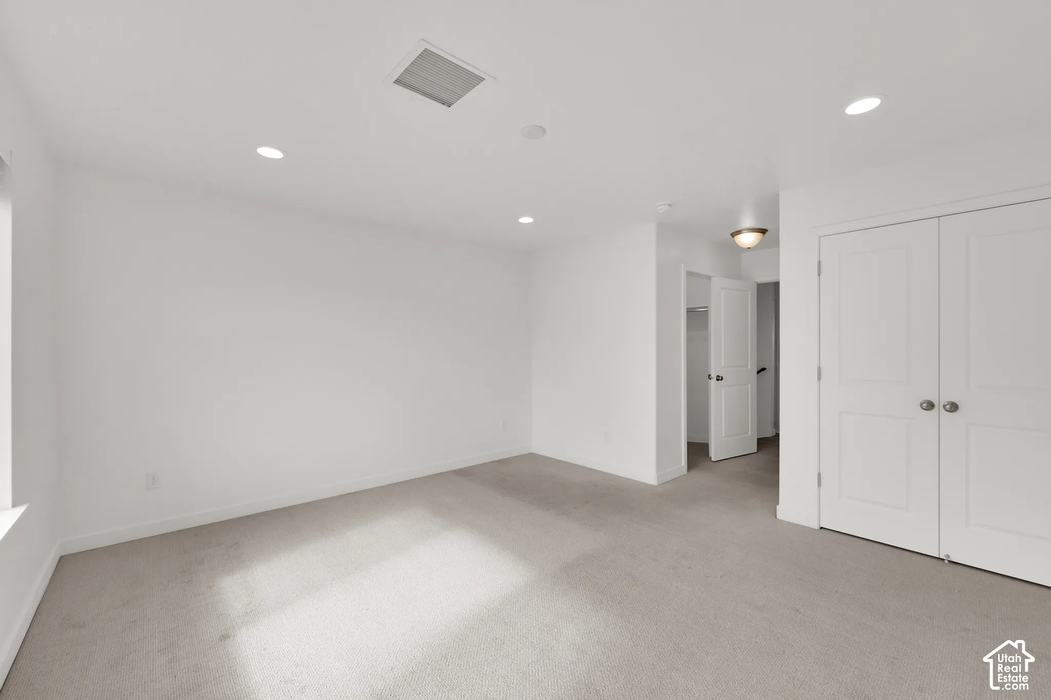 Neutral-toned carpeting, recessed lighting, and double-door closet with panel detailing