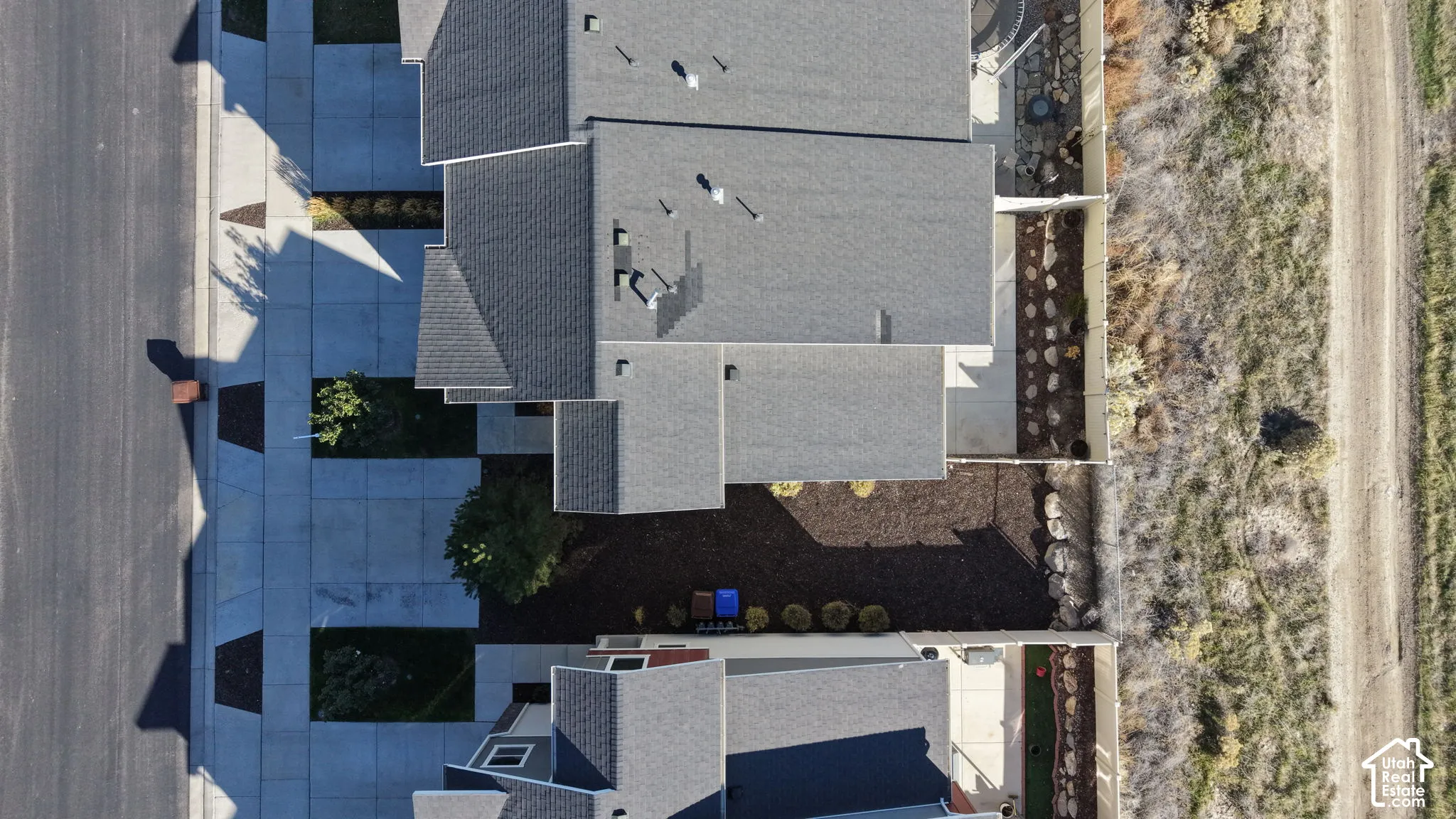 Aerial perspective featuring an asphalt shingle roof, concrete driveway, and mulched landscaping
