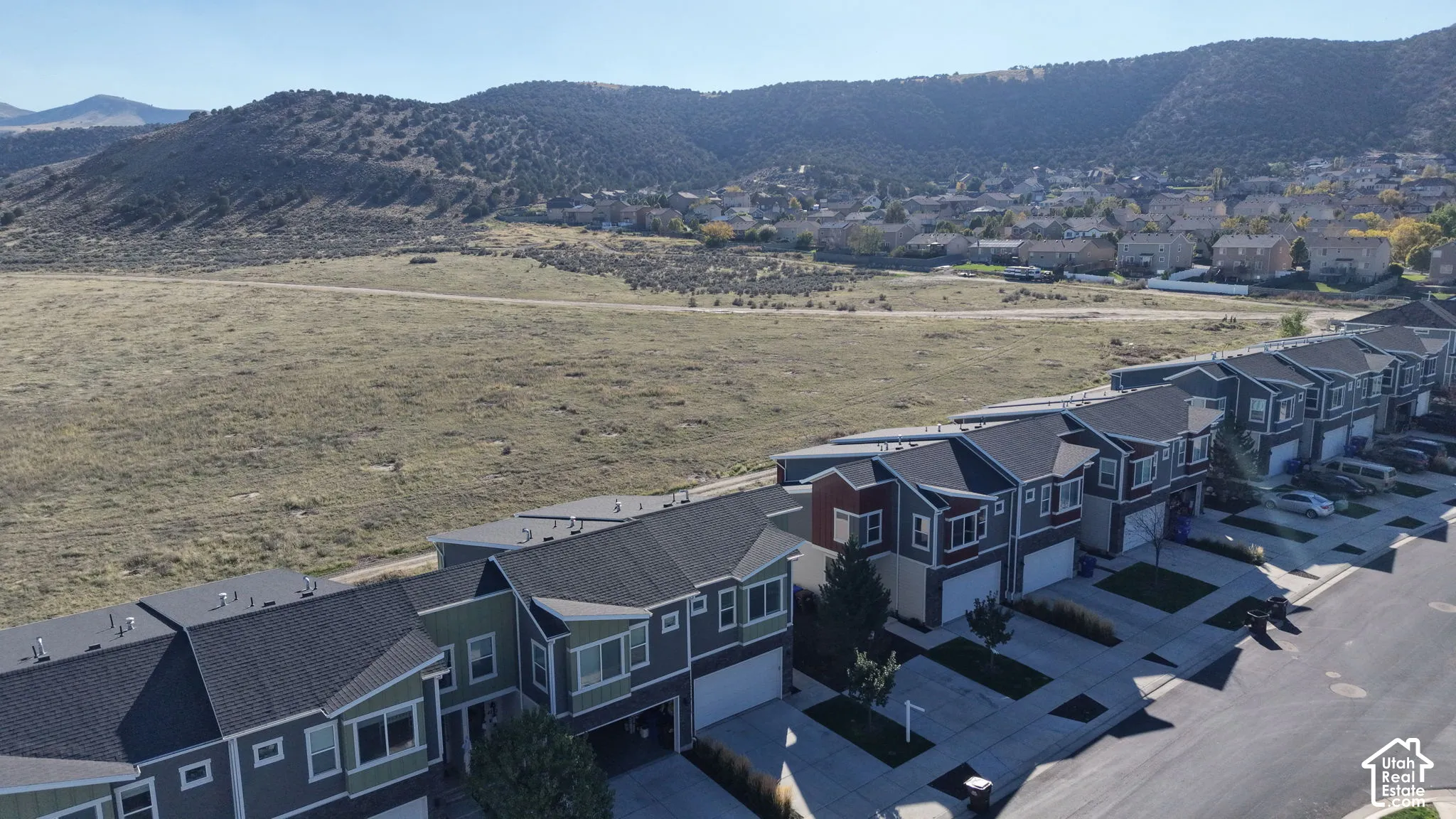 Aerial perspective of multi-level residential structures featuring shingled rooflines, attached garages, and a mountainous backdrop