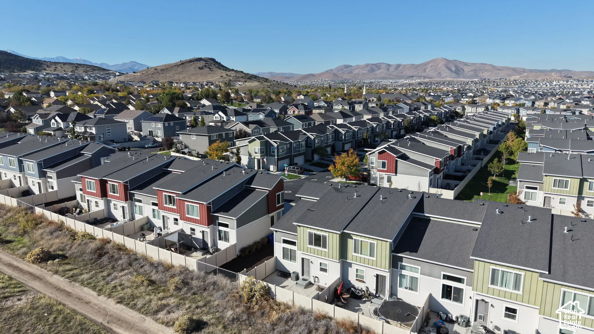 Aerial perspective of multi-story residences featuring shingled roofs, lap siding, and enclosed private rear courtyards, set against a mountainous horizon