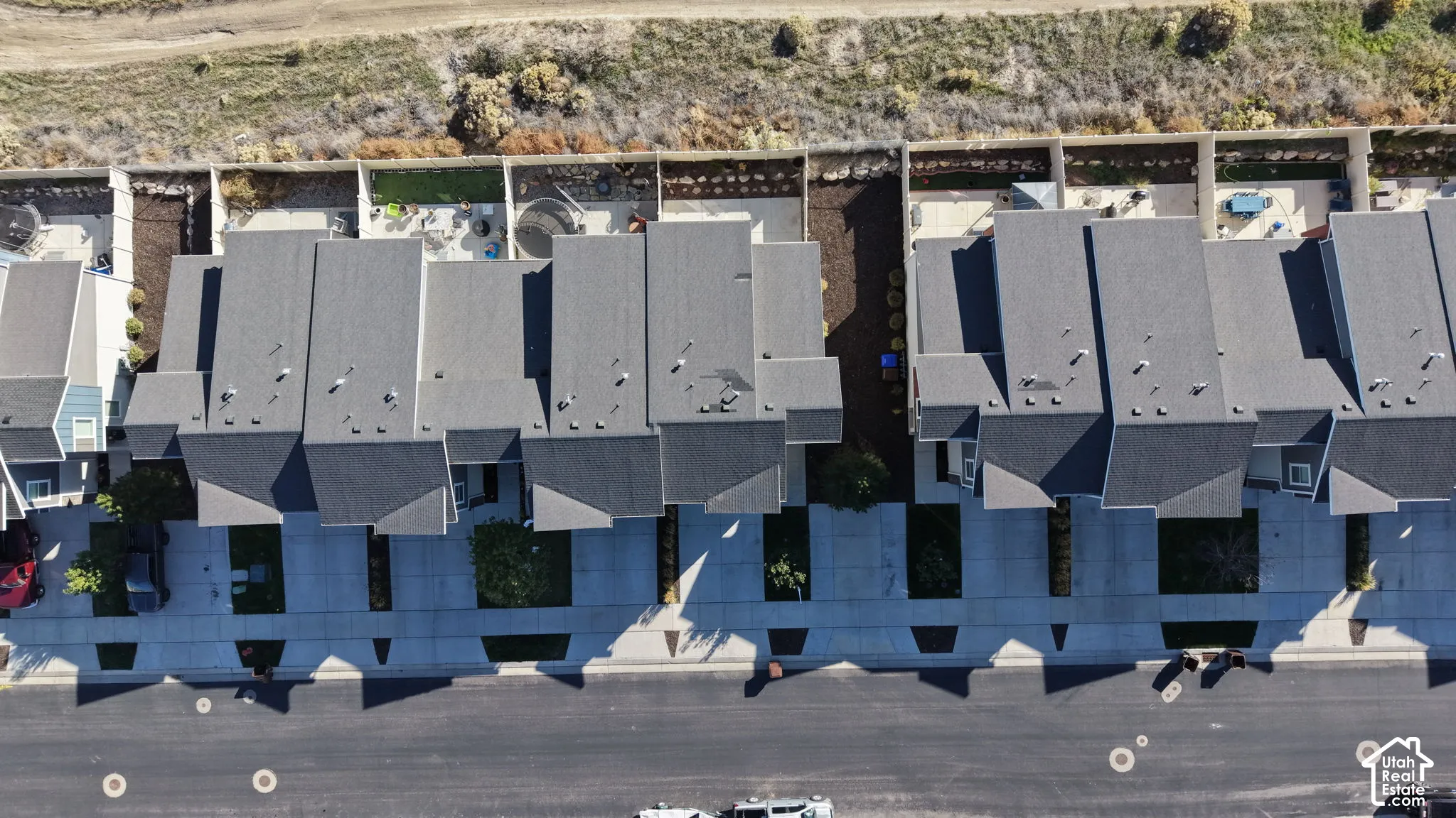 Aerial view featuring multi-unit residences with dark shingle roofing, concrete driveways, and paved street access