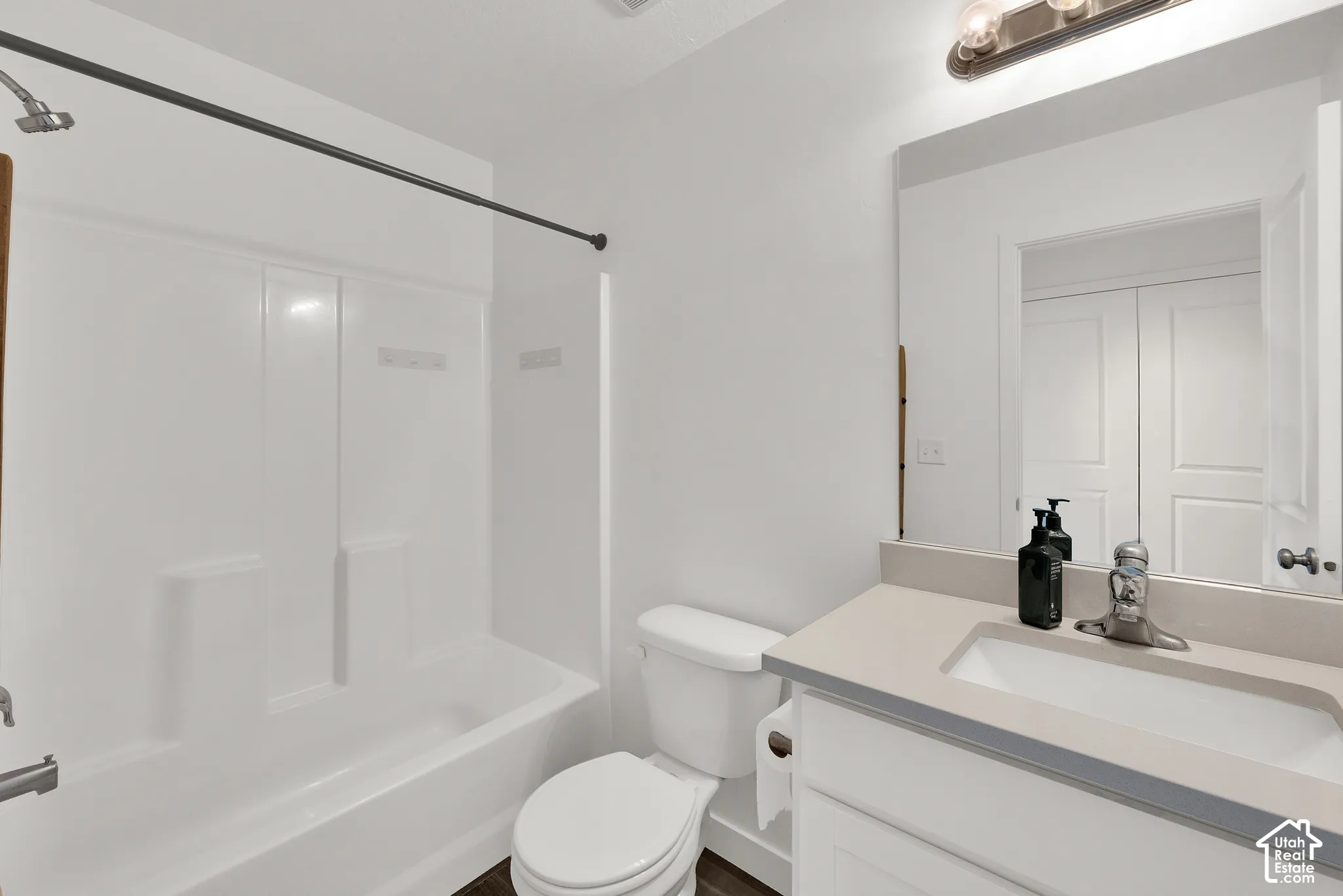 Bathroom featuring a vanity with a neutral-toned countertop and integrated rectangular sink, a combination shower and bathtub enclosure, and a wall-mounted light fixture above the mirror
