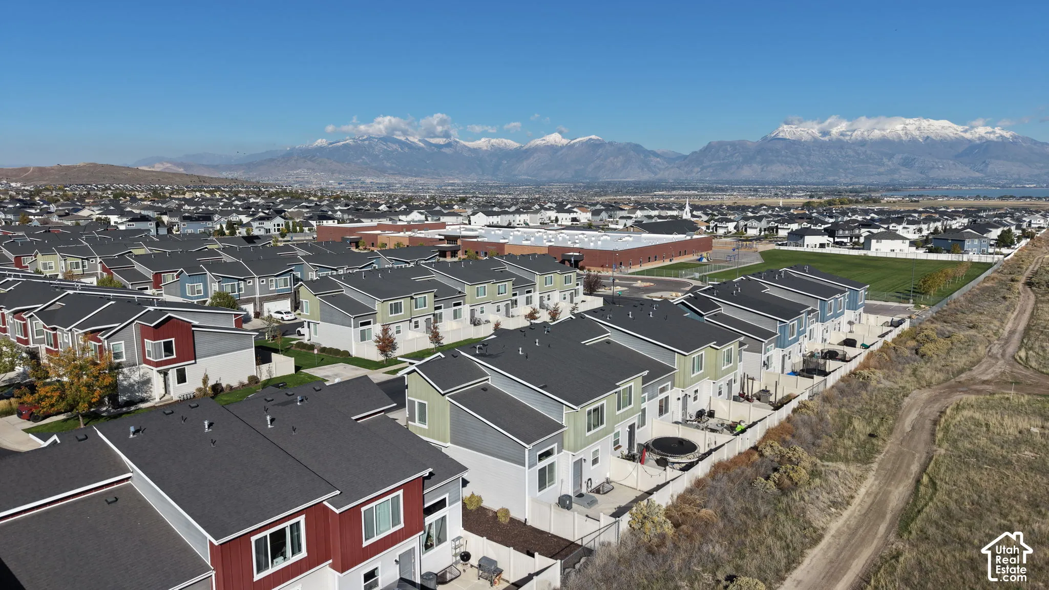 Aerial perspective featuring multi-story residential structures with multi-material exteriors, paved alleyway access, private fenced rear patio spaces, and mountain backdrops