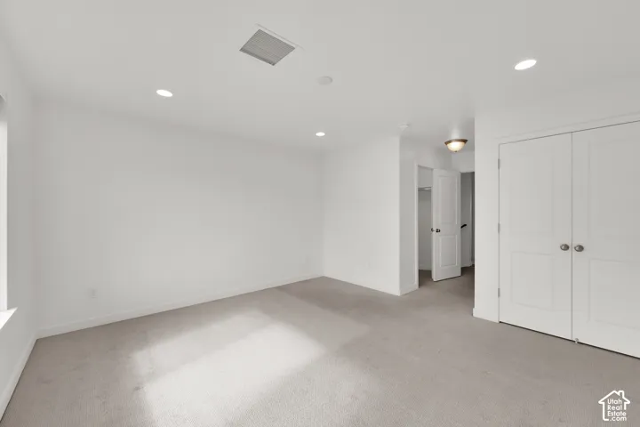Neutral-toned carpeting, recessed lighting, and double-door closet with panel detailing