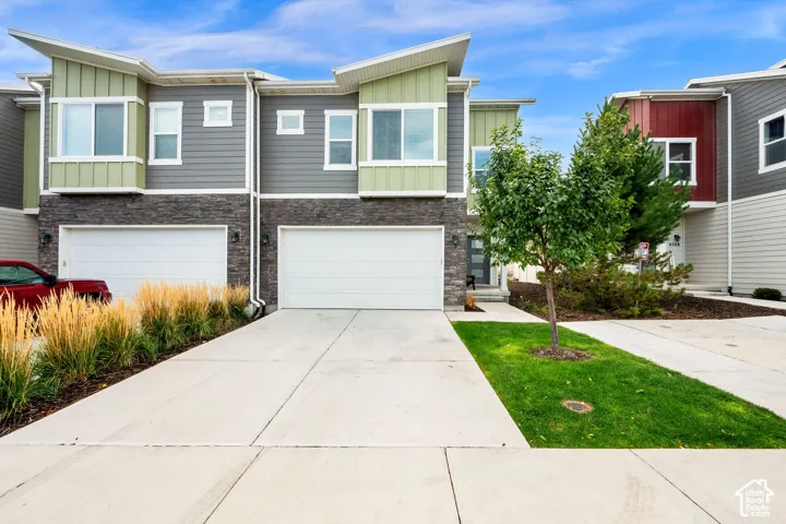 Multi-level exterior featuring a combination of horizontal and vertical siding, stone veneer accents, multi-pane windows, and private garages with concrete driveways