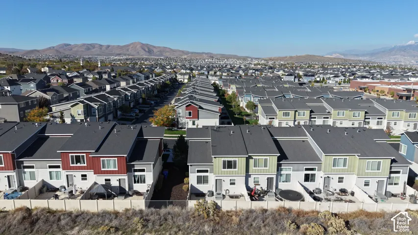 Aerial perspective of multi-family residences featuring vertical panel siding, gabled rooflines, private fenced-in outdoor spaces, and mountain scenery