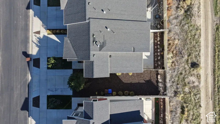 Aerial perspective featuring an asphalt shingle roof, concrete driveway, and mulched landscaping
