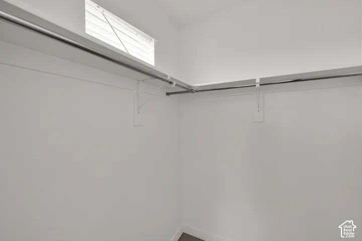 Storage area featuring wrap-around shelving, dual metal garment rods, and a transom window with integrated blinds