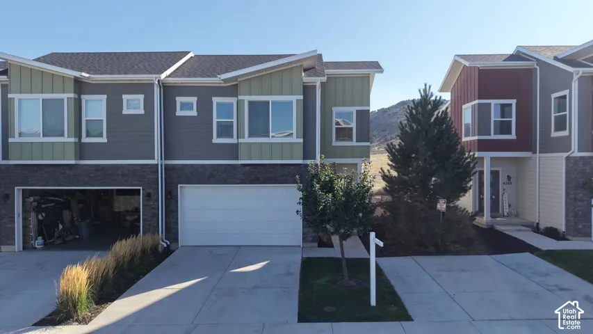 Multi-level exterior featuring a combination of stone veneer and horizontal siding, asphalt shingle roofing, private concrete driveways, and attached garage bays