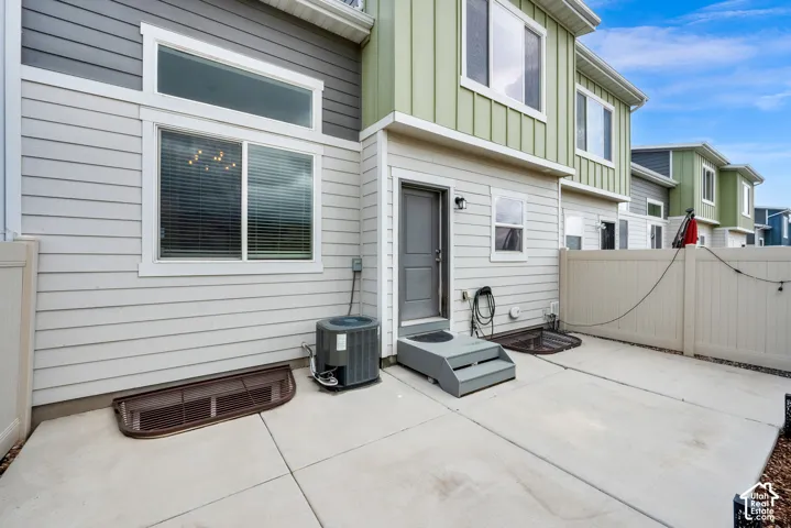 Multi-level exterior featuring horizontal lap and vertical board-and-batten siding, concrete patio, privacy fencing, and window wells