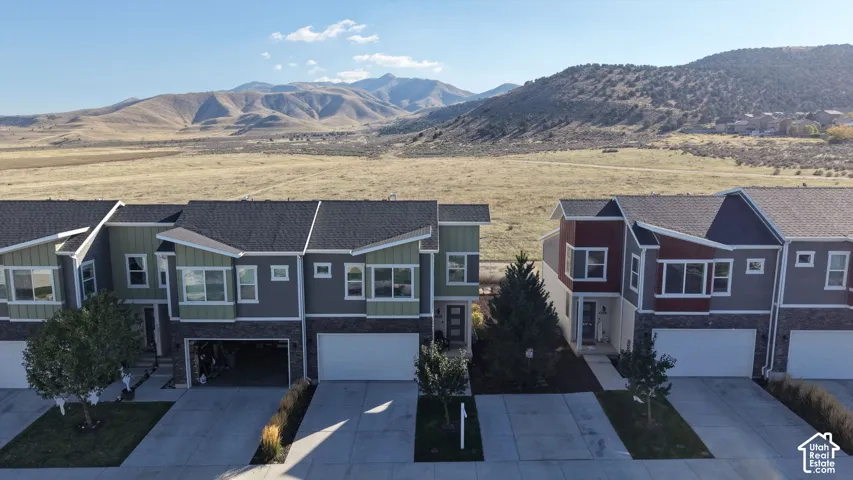 Multi-level residential exterior featuring mixed-material siding, stone veneer accents, pitched rooflines, and mountain scenery