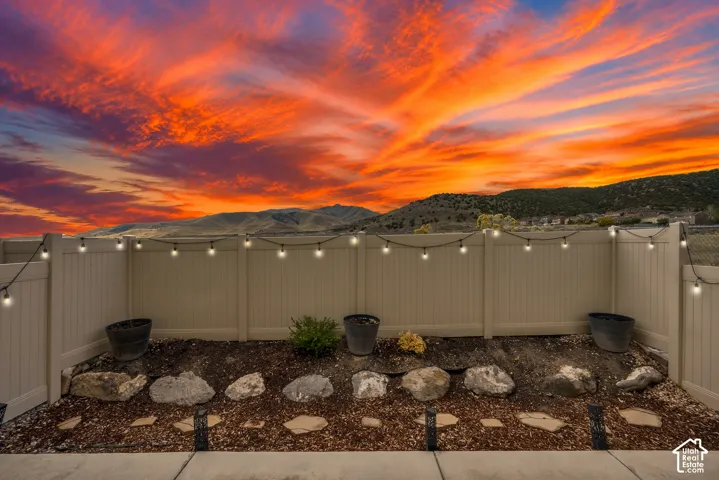 Backyard featuring a vinyl privacy fence, natural stone landscape edging, wood chip ground cover, and a mountain backdrop