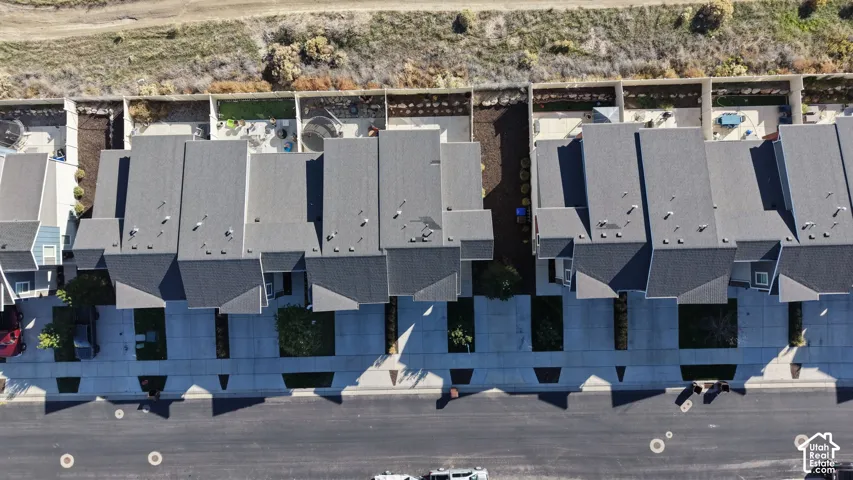 Aerial view featuring multi-unit residences with dark shingle roofing, concrete driveways, and paved street access