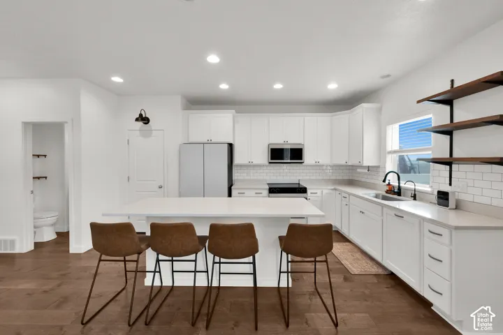 Kitchen featuring white cabinetry, quartz countertops, subway tile backsplash, wood-finish flooring, and open shelving