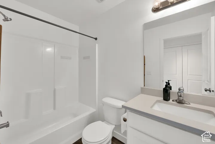 Bathroom featuring a vanity with a neutral-toned countertop and integrated rectangular sink, a combination shower and bathtub enclosure, and a wall-mounted light fixture above the mirror