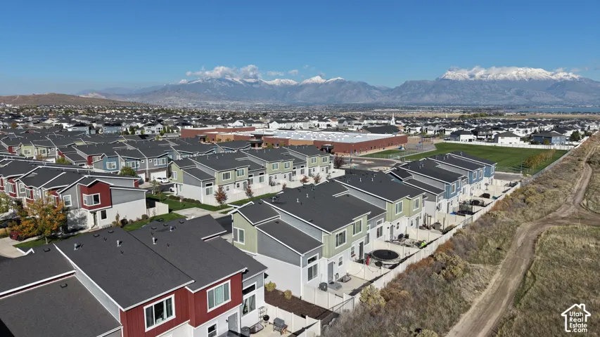 Aerial perspective featuring multi-story residential structures with multi-material exteriors, paved alleyway access, private fenced rear patio spaces, and mountain backdrops