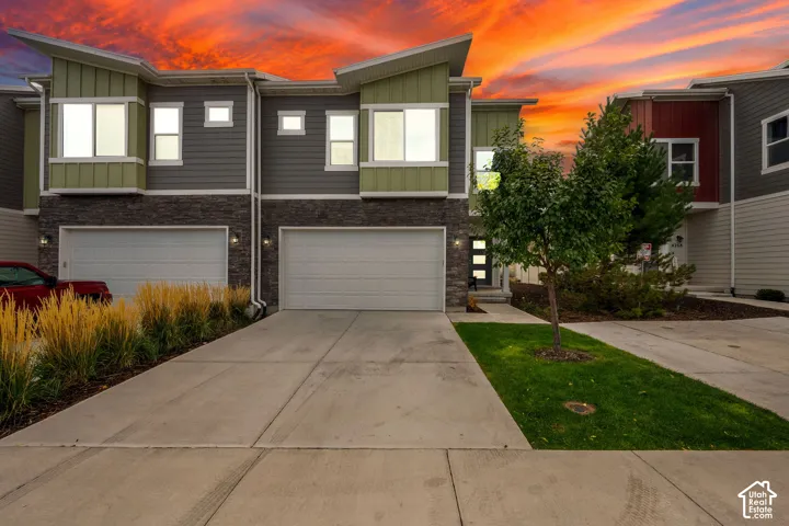 Contemporary exterior featuring multi-toned horizontal siding, stone veneer accents, shed-style rooflines, attached two-car garages, and concrete driveways