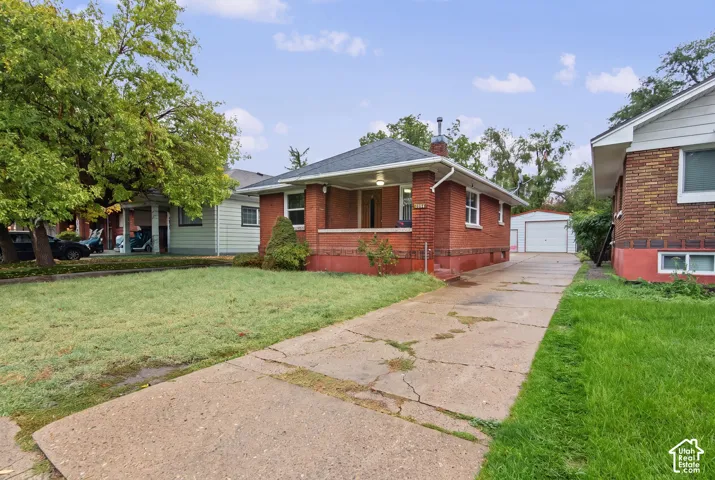 Brick exterior featuring a covered front porch, hipped roofline, and a detached single-car garage