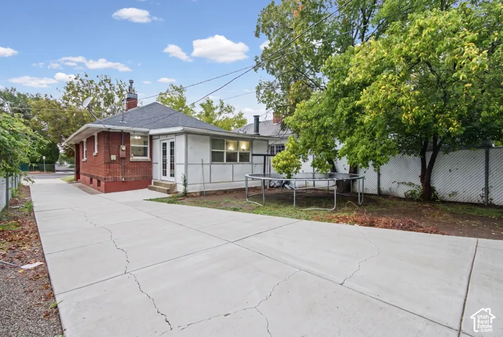 Exterior featuring red brick and white-paneled siding, concrete driveway, and white lattice fencing