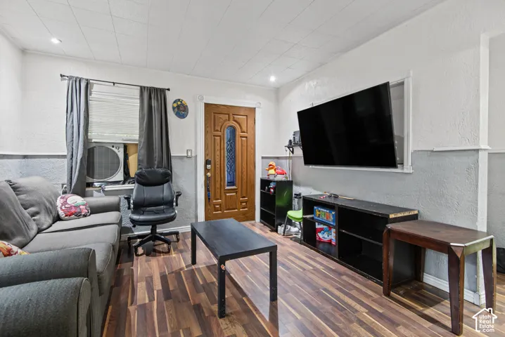 Interior space featuring wood-finish flooring, a textured two-tone wall finish, and a raised-panel entry door with decorative glass inlay