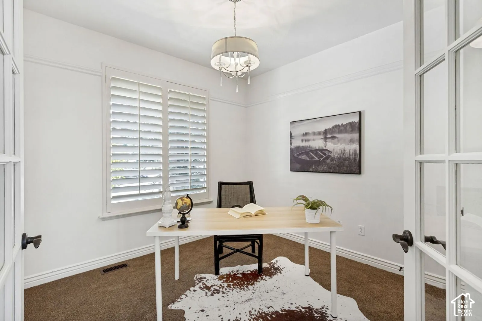 Interior space featuring French doors, white plantation shutters, neutral carpeting, and a drum-style chandelier with crystal accents