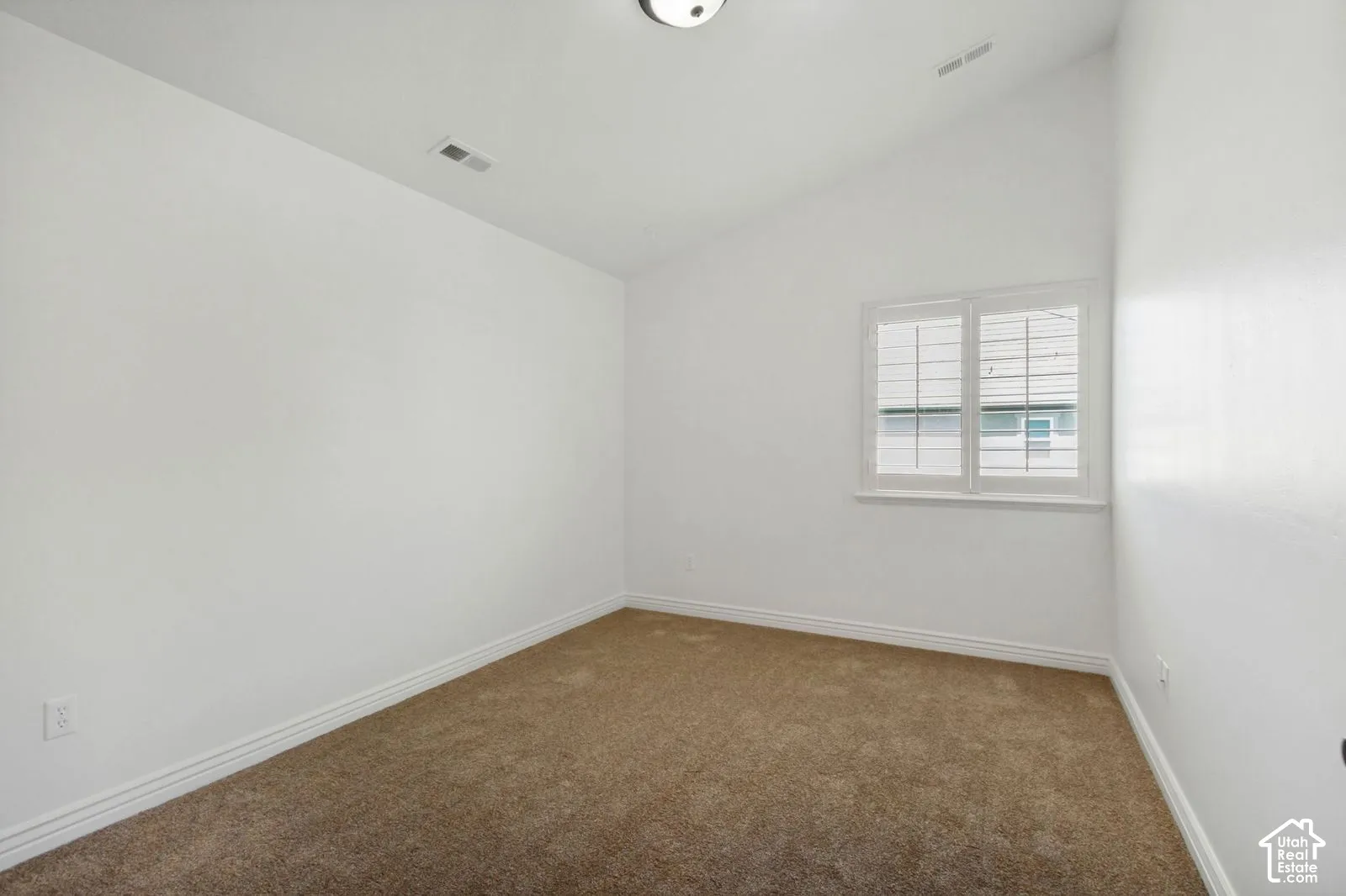 Vaulted ceilings, neutral carpeting, and plantation-style window shutters
