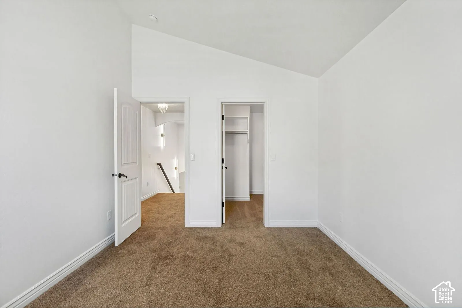 Vaulted ceiling, neutral wall-to-wall carpeting, and walk-in closet with built-in shelving