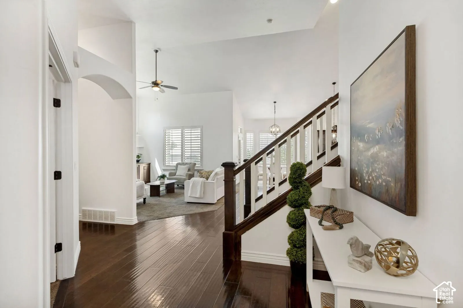 Entryway featuring wood-finish flooring, vaulted ceilings, and a staircase with stained-wood handrails