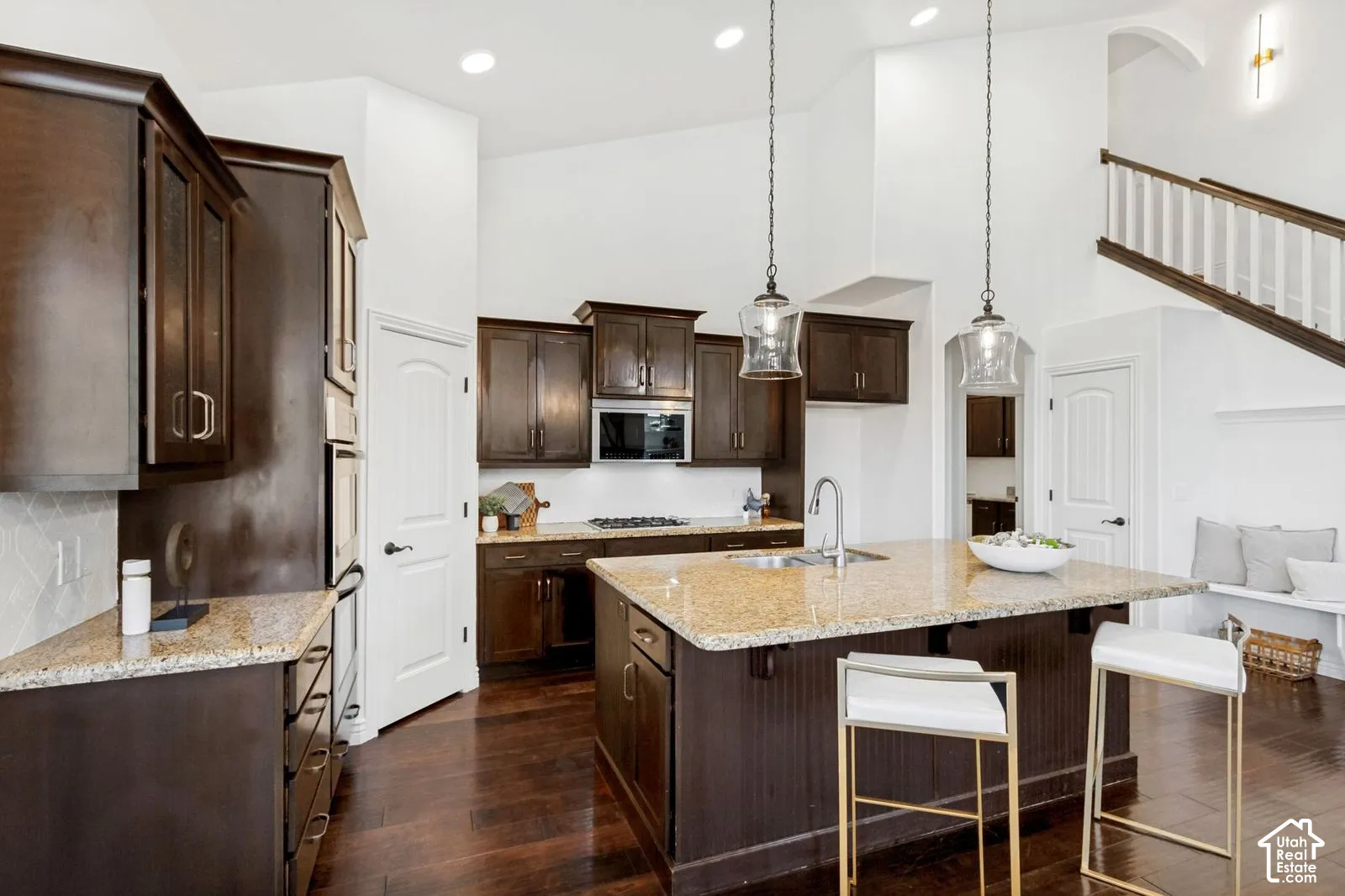 Kitchen featuring dark wood cabinetry, stone countertops, central island, wood-finish flooring, and vaulted ceilings