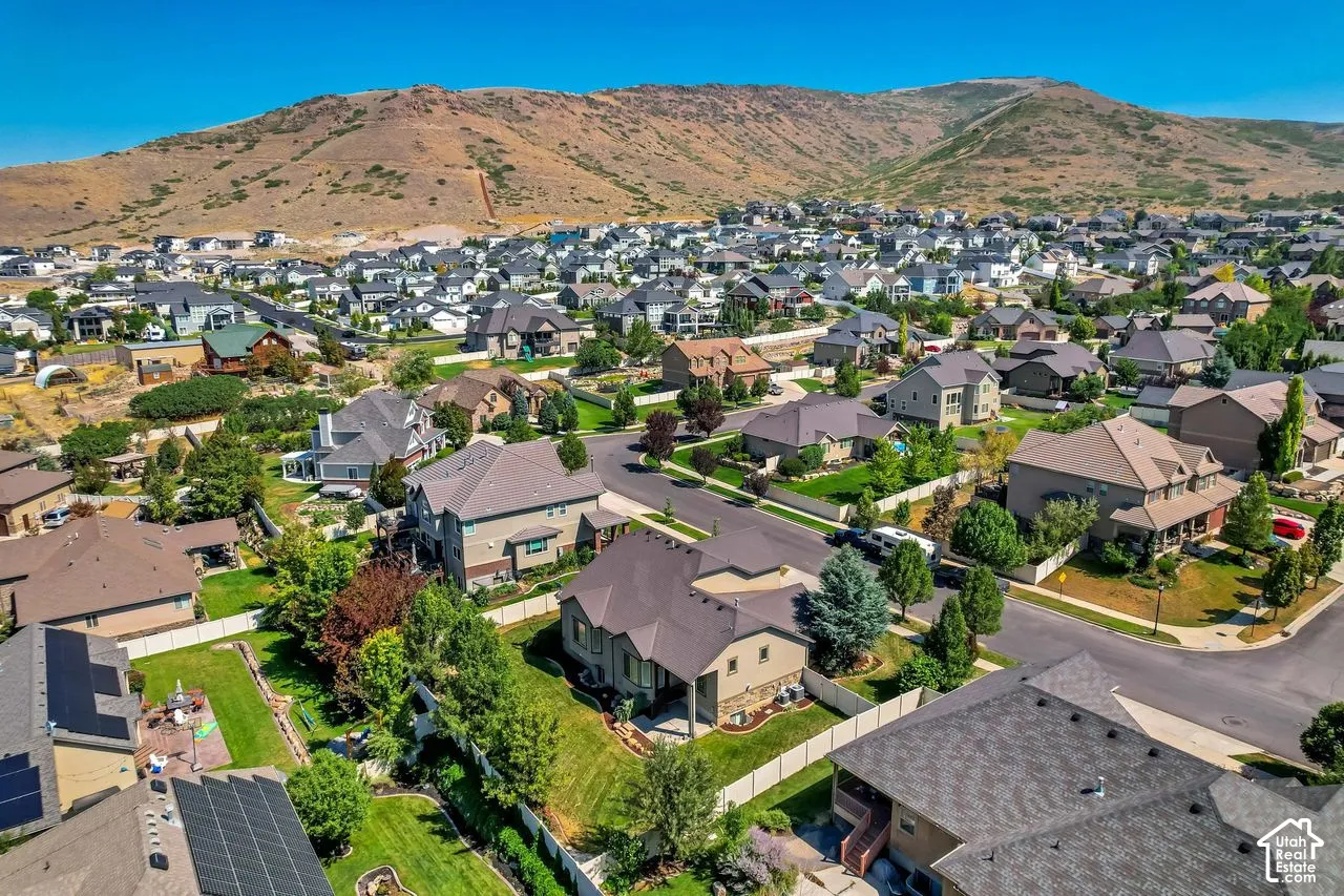 Aerial perspective of a residential neighborhood featuring mountain topography, asphalt streets, and mature landscaping