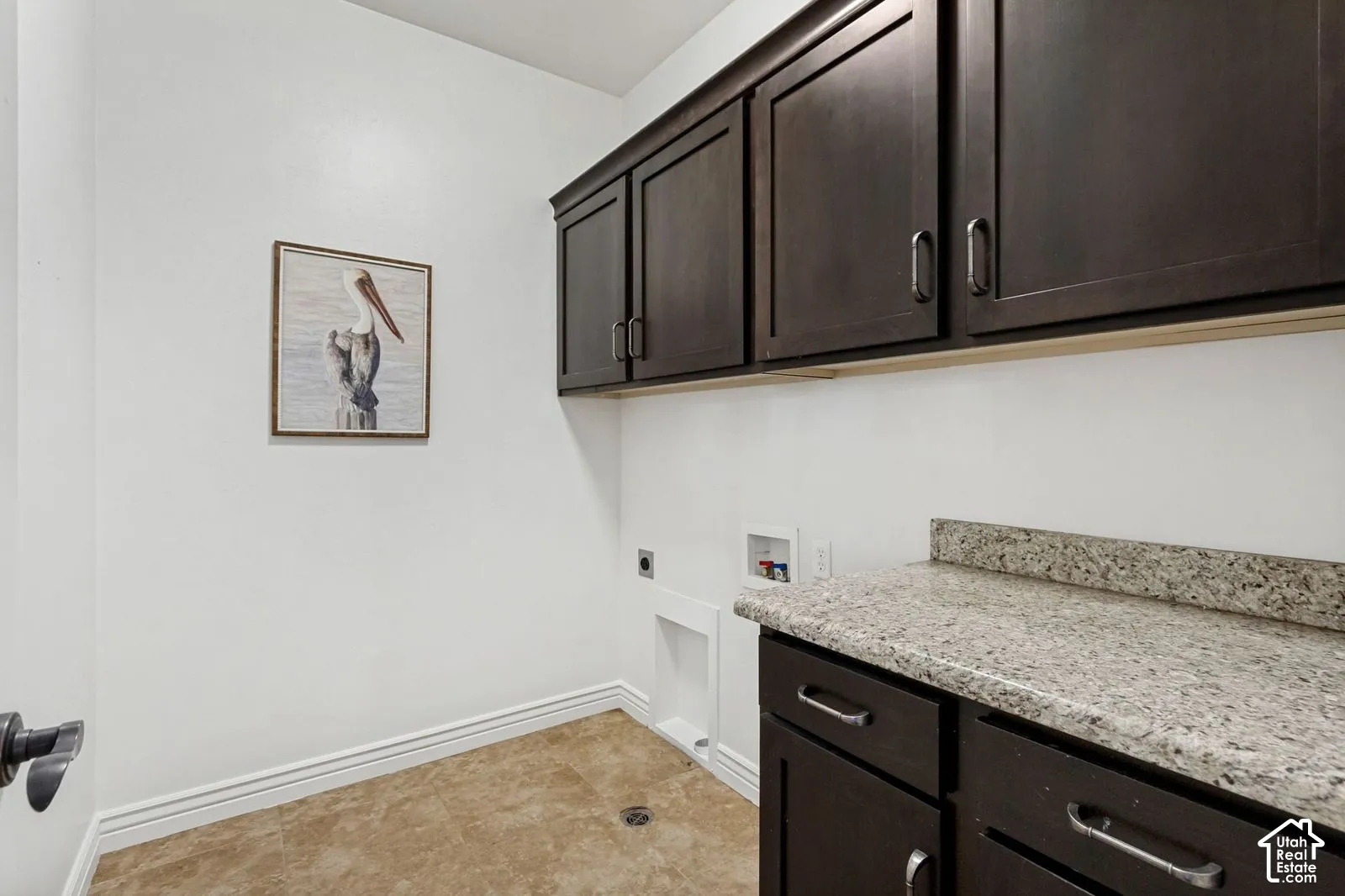 Dark-finish wood cabinetry, stone-texture countertop, integrated sink, and tile flooring