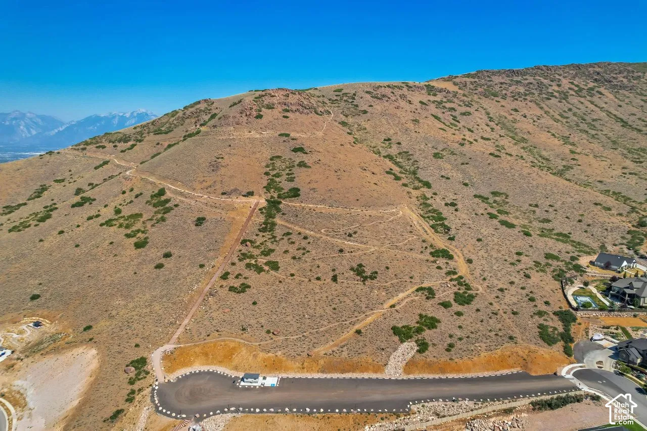 Aerial perspective of a hillside property featuring expansive natural terrain, sloping topography, and mountain backdrops