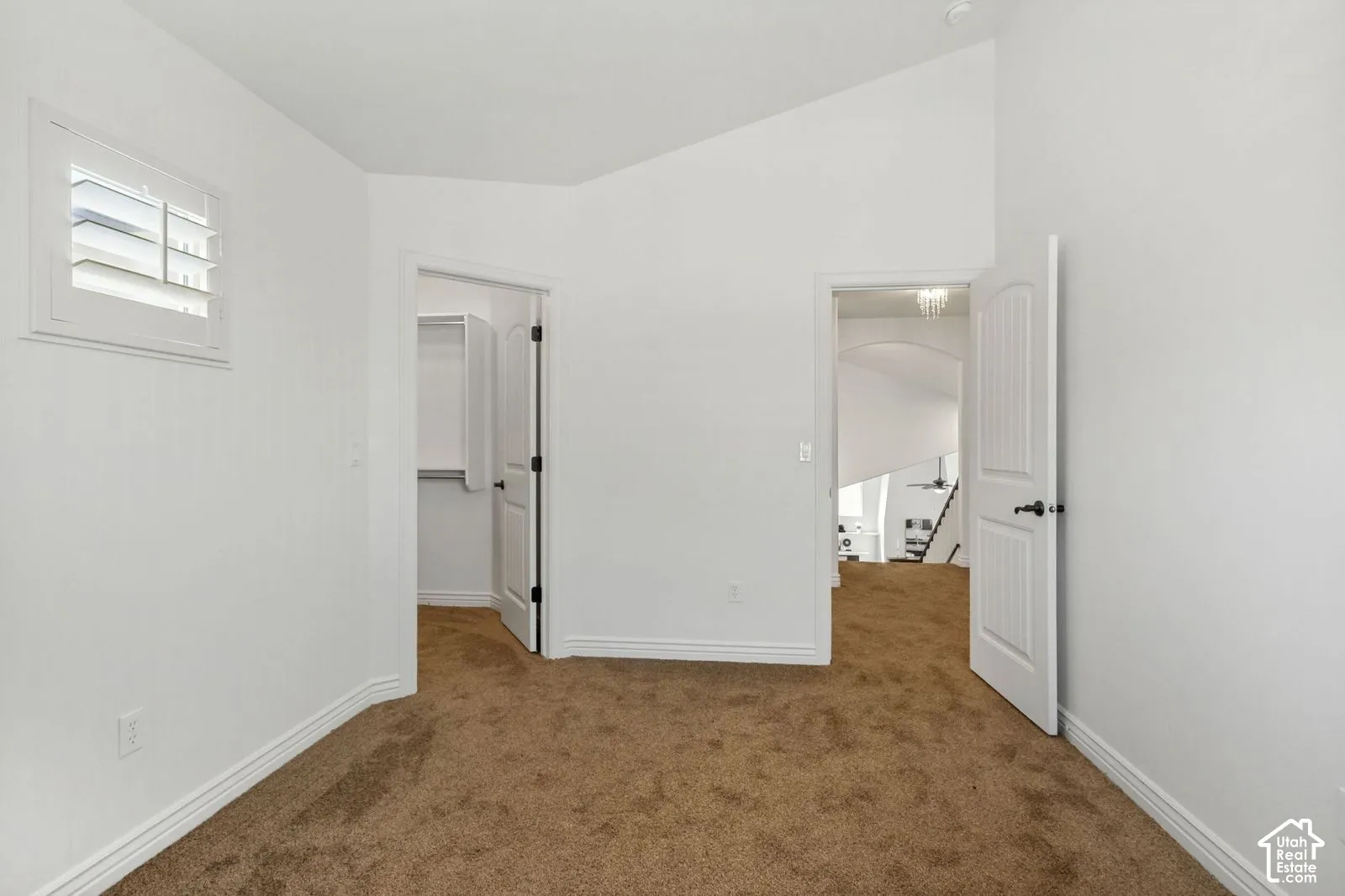 Vaulted ceilings, interior shutter window treatments, carpeted flooring, and white two-panel interior doors