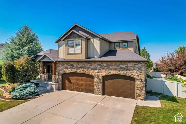 Multi-level exterior featuring a stone facade, shingle roof, vertical siding accents, a three-car garage, and a covered front porch