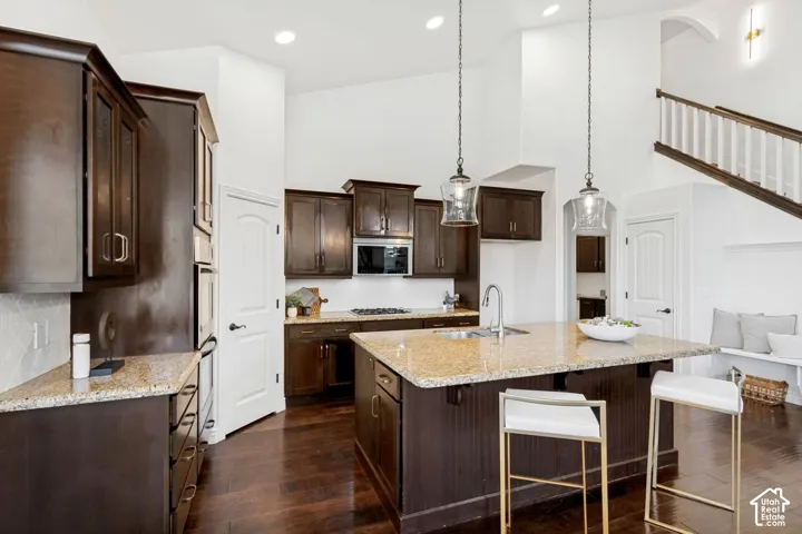 Kitchen featuring dark wood cabinetry, stone countertops, central island, wood-finish flooring, and vaulted ceilings