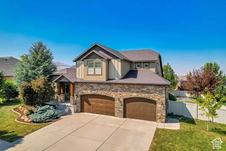 Multi-level exterior featuring a stone facade, board-and-batten siding, dual-car garage, and a covered entryway