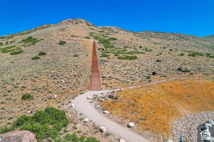 Structural metal staircase ascending a hillside landscape featuring native vegetation and natural stone topography