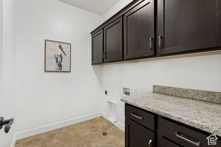 Dark-finish wood cabinetry, stone-texture countertop, integrated sink, and tile flooring