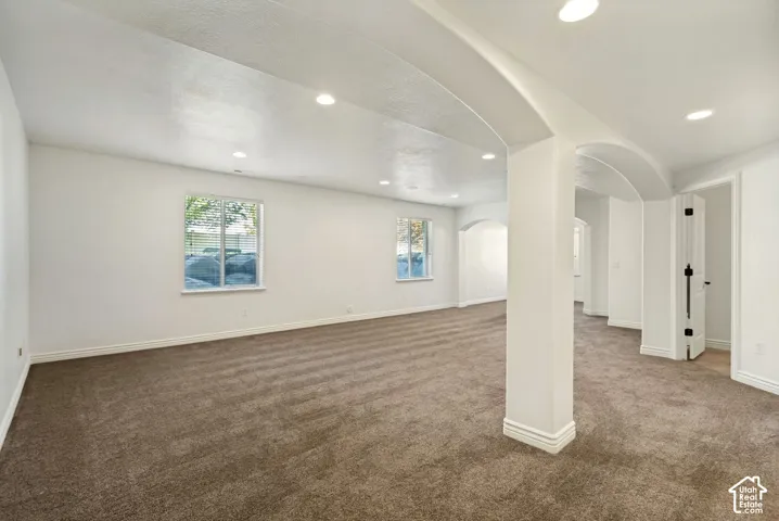 Open-concept interior featuring archway architectural detailing, wall-to-wall carpeting, and recessed lighting