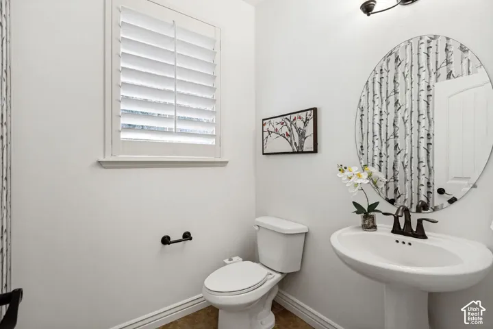 Powder room featuring a white pedestal sink with a bronze-finish faucet, an oval wall-mounted mirror, plantation shutters, and bronze-finish hardware