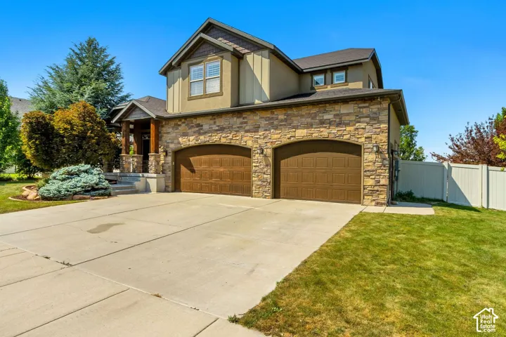 Two-story exterior featuring multi-textured siding, stone veneer masonry, two arched garage doors, and a covered front porch with timber support columns