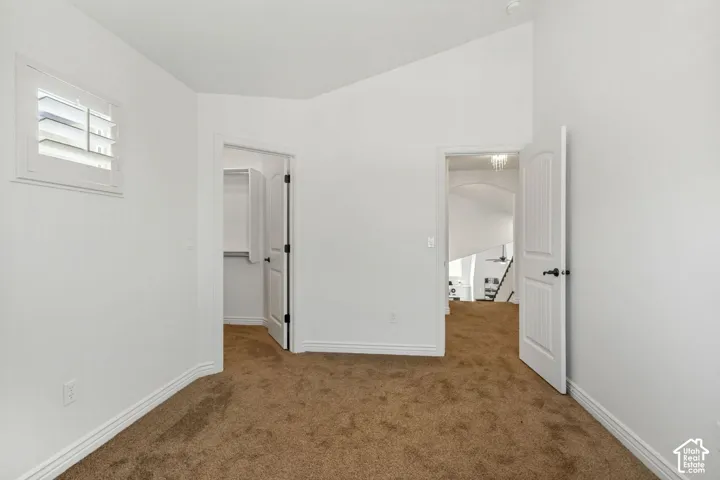 Vaulted ceilings, interior shutter window treatments, carpeted flooring, and white two-panel interior doors