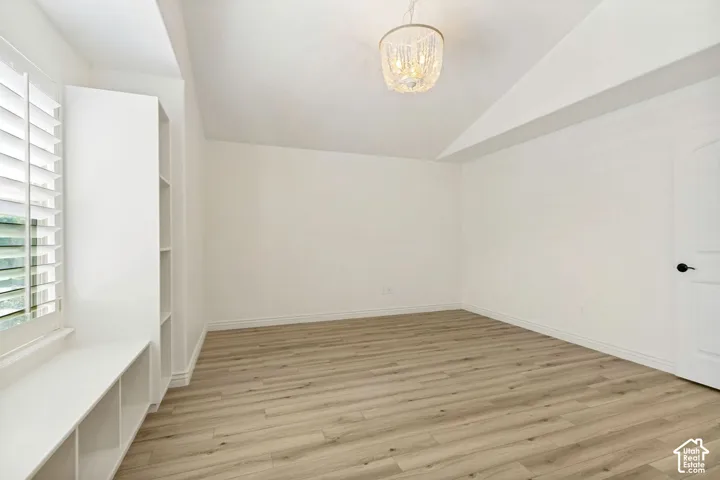 Vaulted ceilings, wood-finish flooring, built-in shelving with window seating, plantation shutters, and a crystal-style chandelier