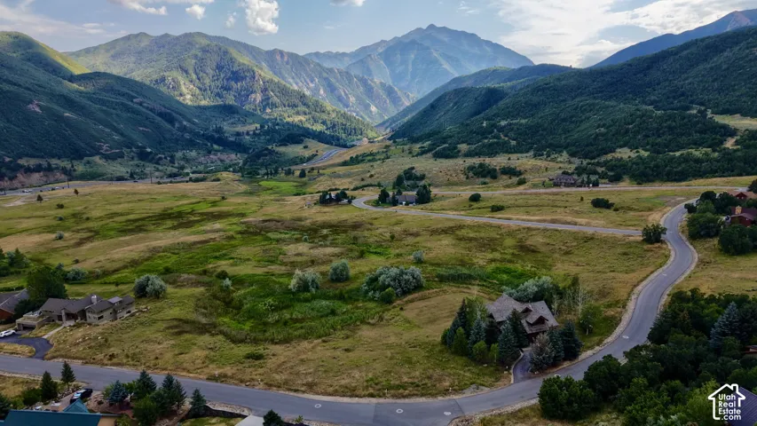 Aerial perspective featuring sprawling mountain terrain, expansive native grasslands, and winding paved thoroughfares