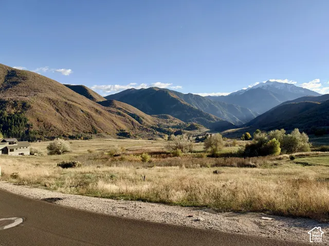 Expansive landscape featuring rolling terrain and a backdrop of prominent mountain ranges