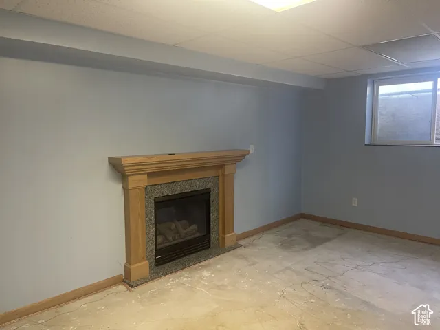 Fireplace featuring a stone-surround insert and wooden mantel, drop ceiling, and horizontal window