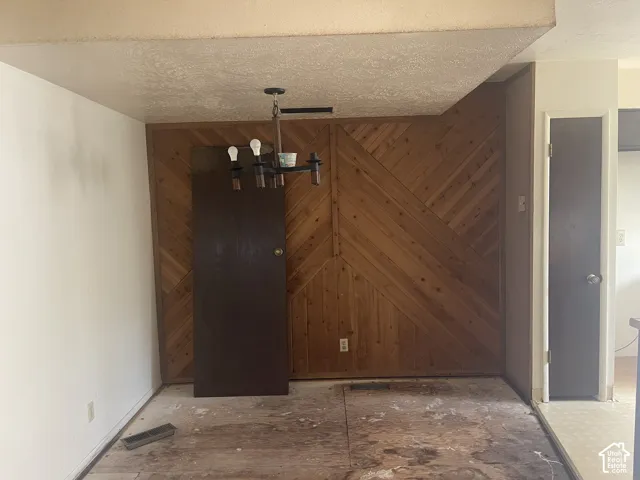 Wood-paneled accent wall with diagonal planking, multi-arm metal chandelier, and solid-core interior doors