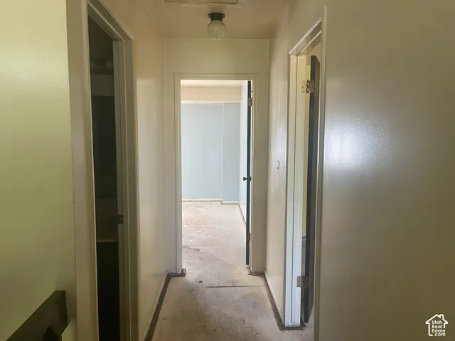 Interior hallway featuring neutral-toned walls, solid-core doors, and a flush-mount ceiling light fixture